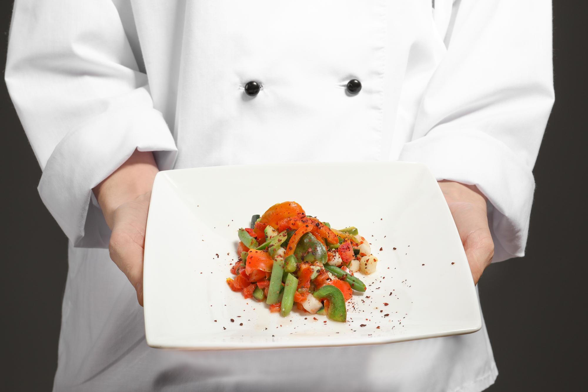 Chef che prepara un piatto moderno su banco in legno